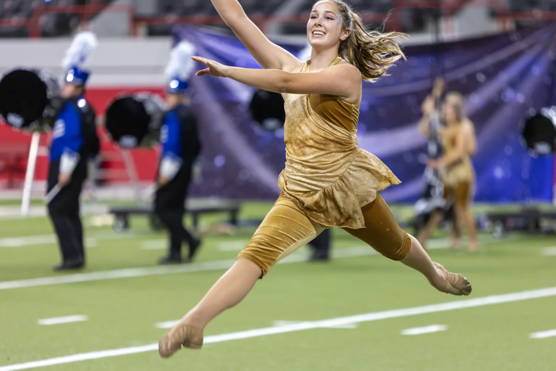 Color guard performer leaping across a football field